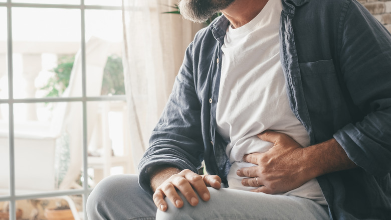 man holding stomach near window