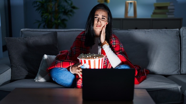 woman with popcorn touching cheek