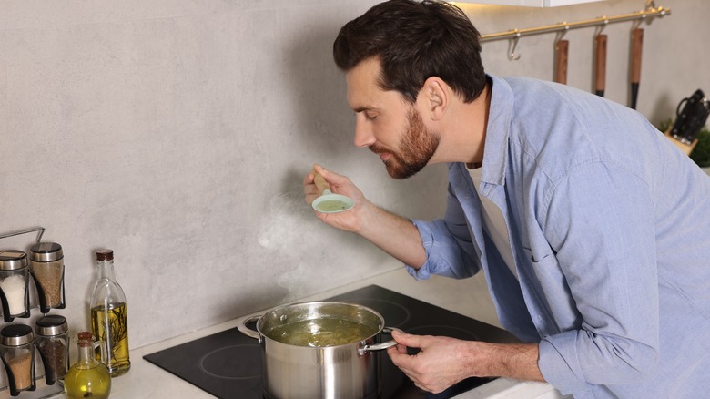 Man tasting soup on stove