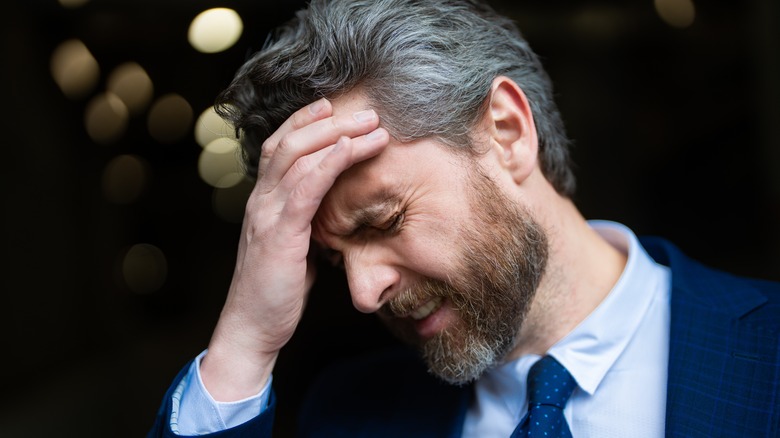 man with migraine holding head