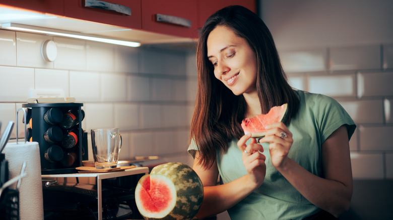 Woman eating watermelon at night