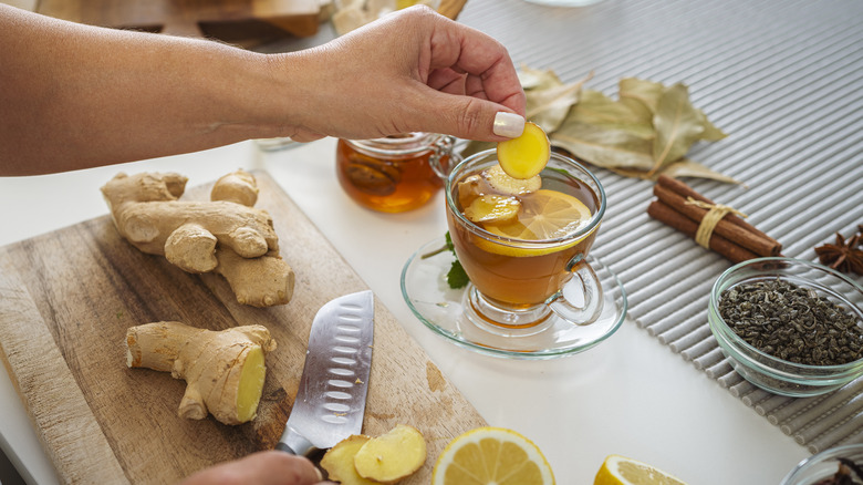 woman's hands preparing lemon and ginger tea