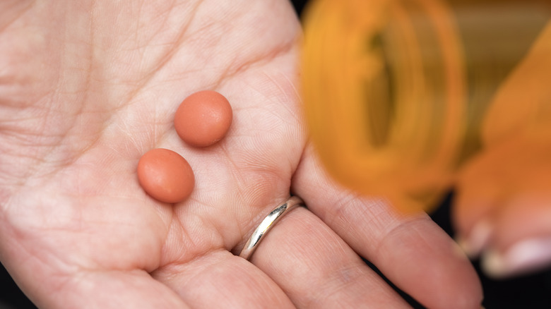 two ibuprofen pills on a woman's hand