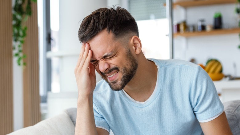 man wincing in headache pain