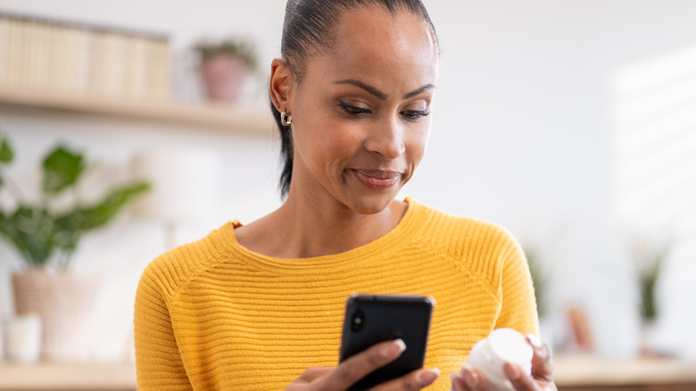 woman checking pill bottle for aspirin and ibuprofen