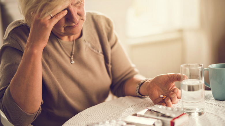Older woman in pain about to take painkillers