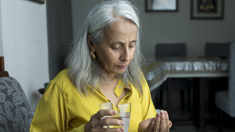 Senior woman taking medication with water