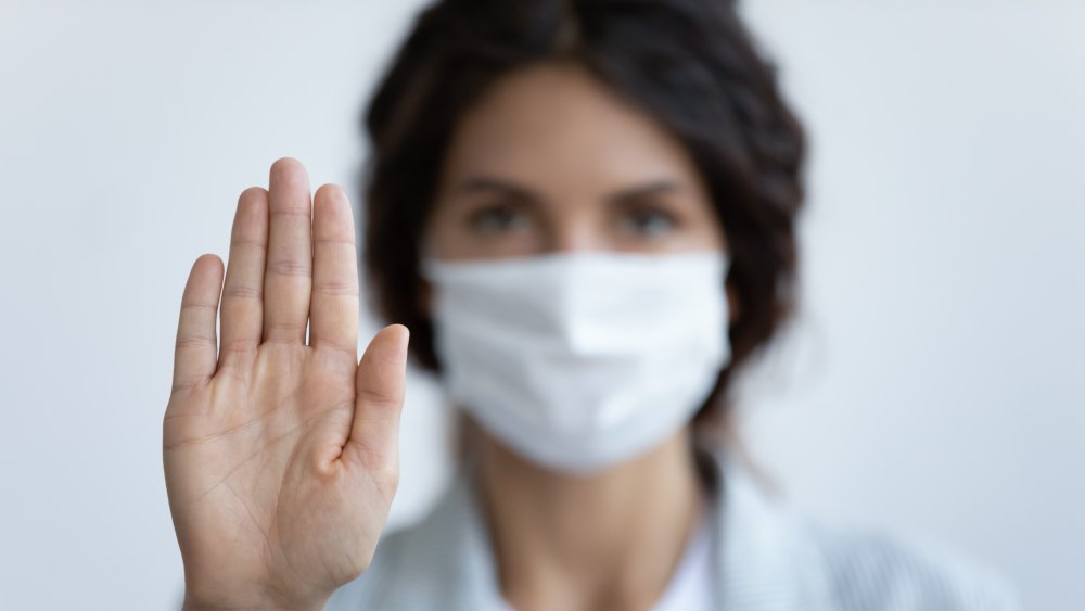 woman with mask makes stop hand motion