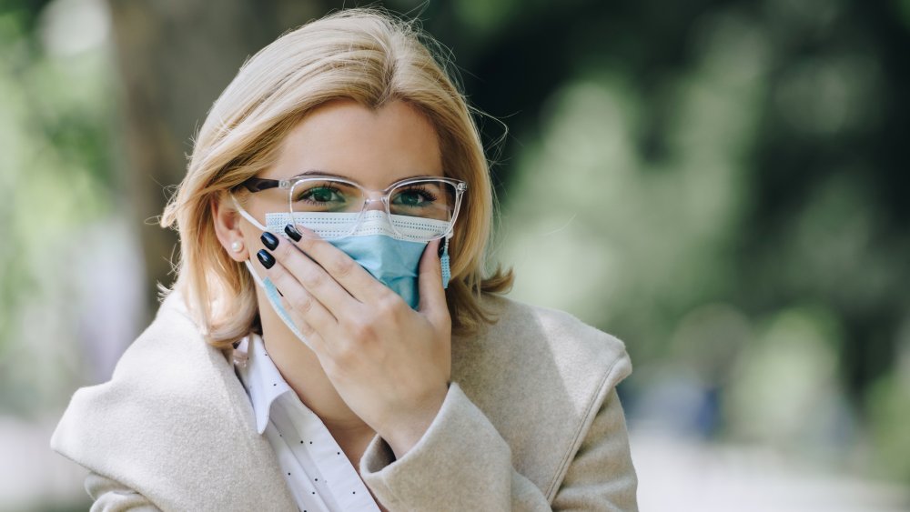 woman touching face mask