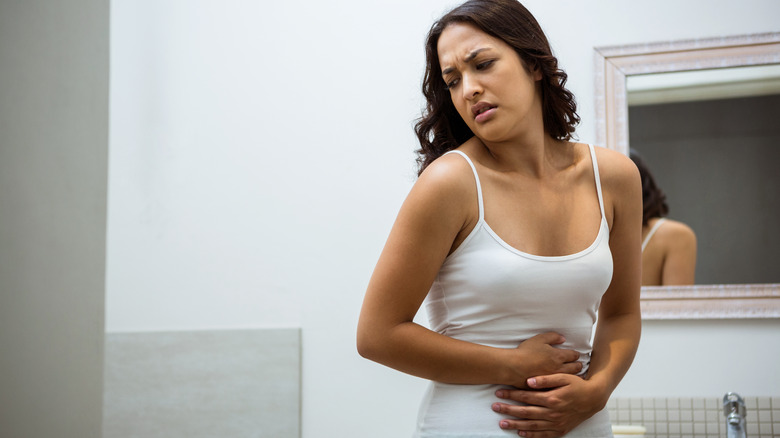 Woman in bathroom with stomach pain