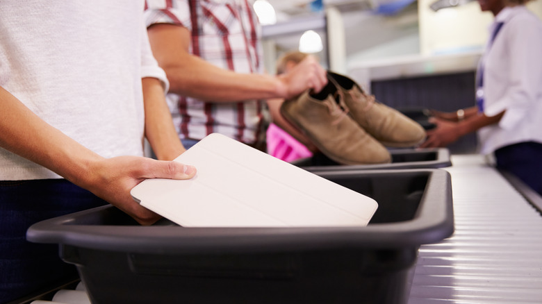 Man putting laptop in security bin