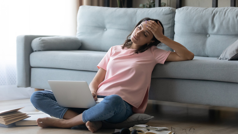 A fatigued woman leans on her couch