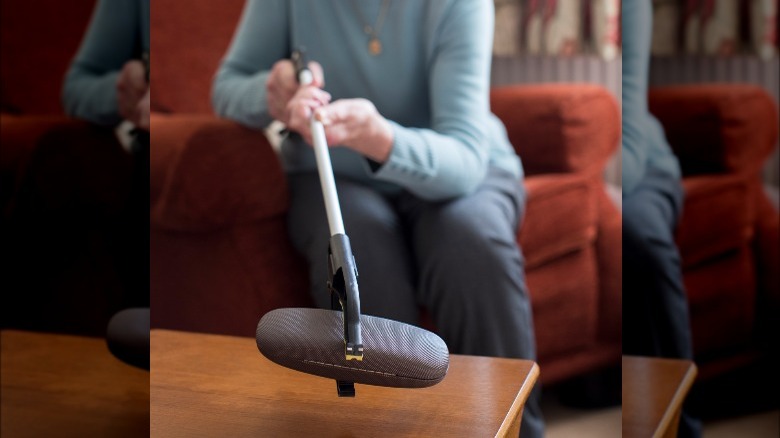 woman using grabber to pick up eyeglass case