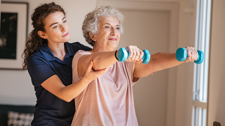 physical therapist working with an older woman lifting weights