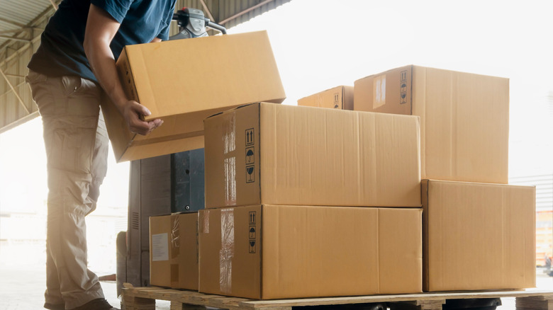 man lifting packages stacked on a pallet