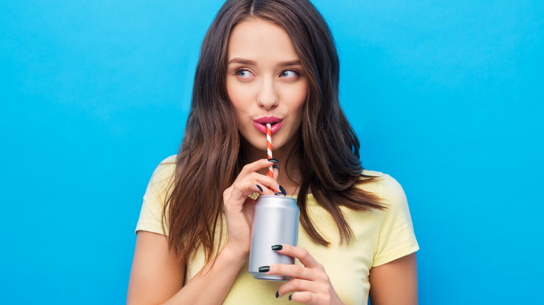 Girl drinking a can of soda through a straw