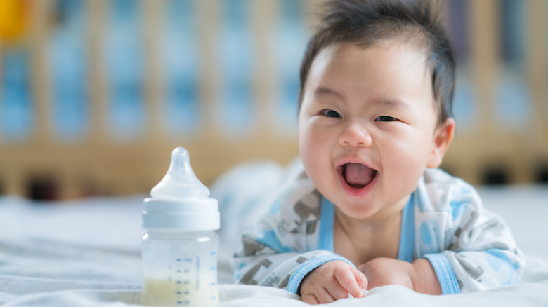 baby smiling with bottle of formula in front of him