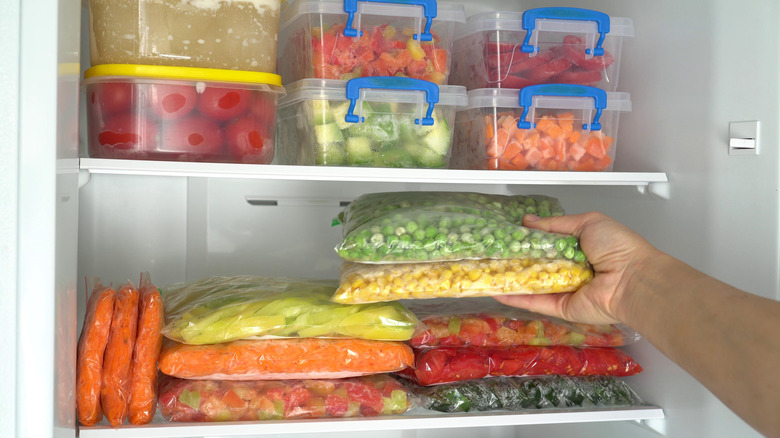 hand reaching into freezer and pulling out frozen vegetables