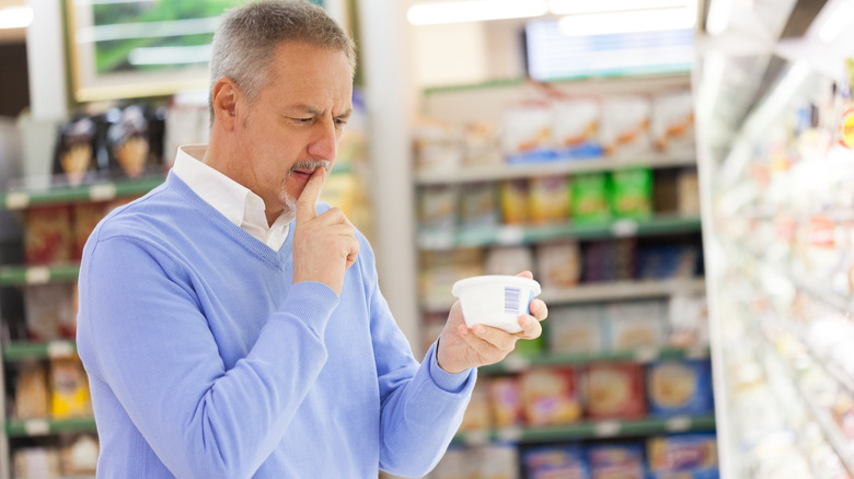 middle-aged man in grocery store looking puzzled over food package