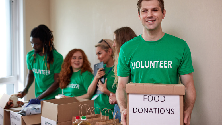 young male food bank volunteer holding box of donations