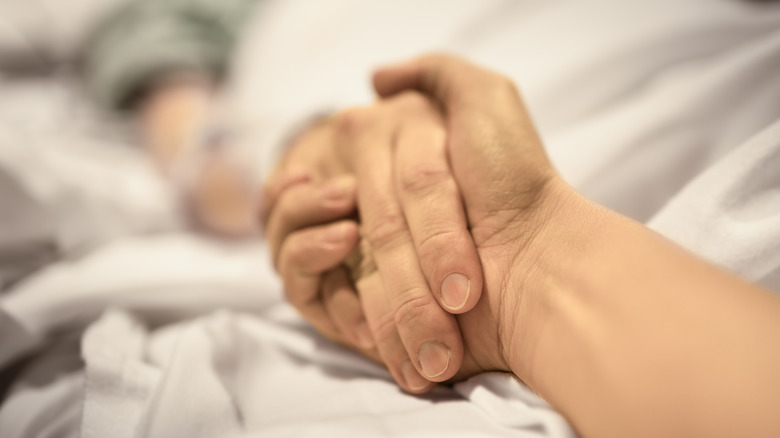 Two people are holding hands at a hospital