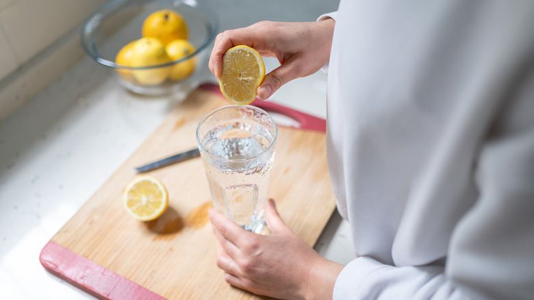woman squeezing lemon into water