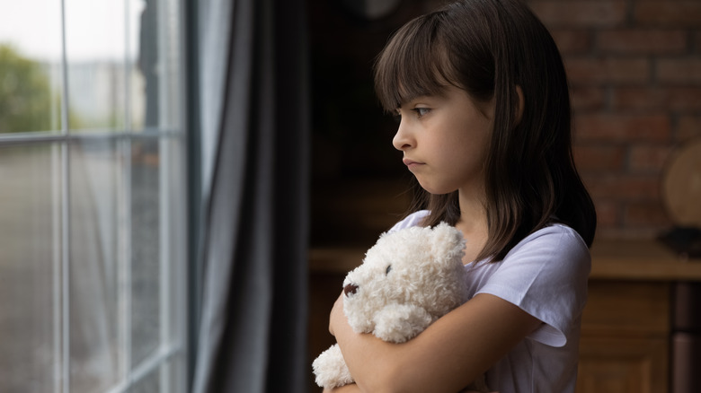 young girl looking outside window