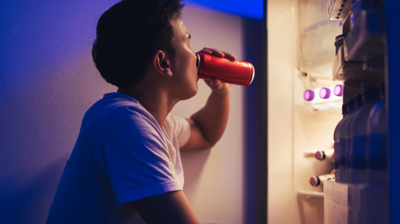 man binge eating by fridge