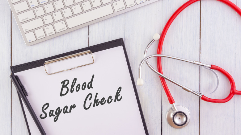 Blood sugar check on notepad with stethoscope and keyboard
