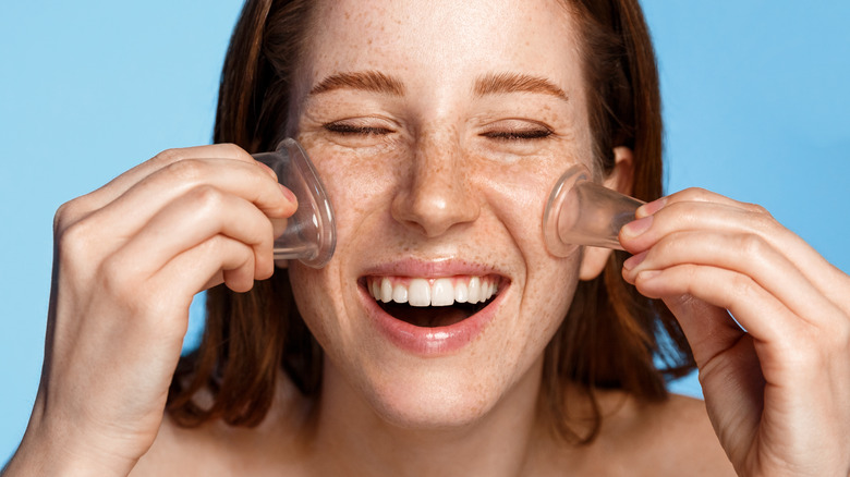 Woman performing facial cupping