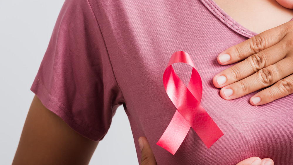 woman wearing a pink shirt with a breast cancer awareness ribbon on her breast