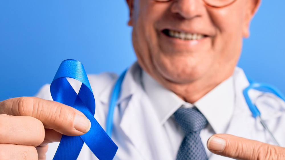 male doctor holding a blue colon cancer awareness ribbon
