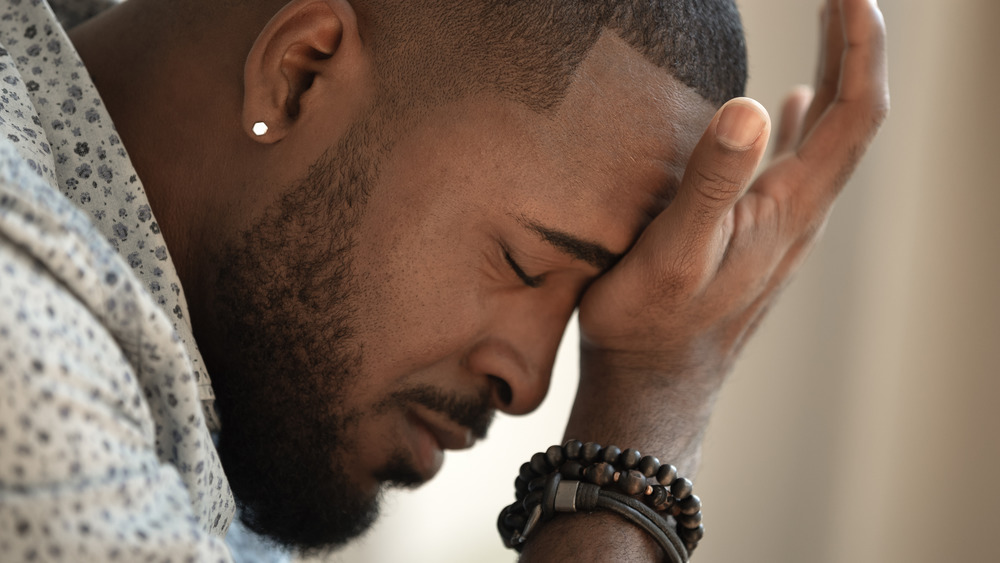 African American man with his eyes closed and his hand on his forehead