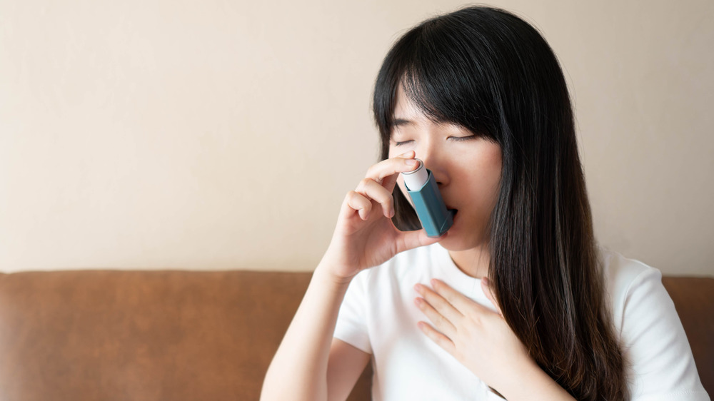 young Asian woman using an asthma inhaler