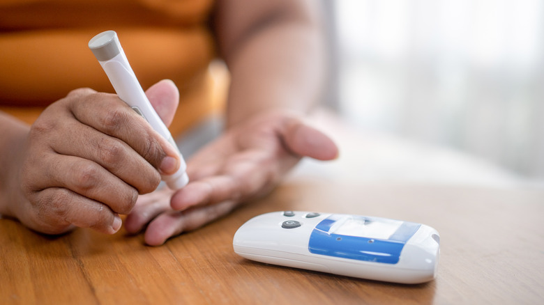 woman's hand using portable glucose monitor