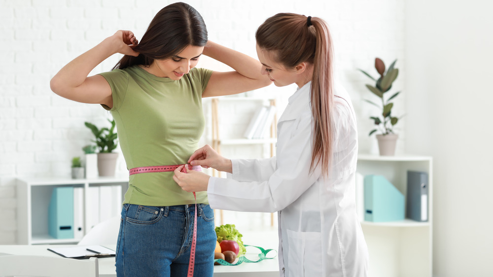 nutritionist measuring woman's waist