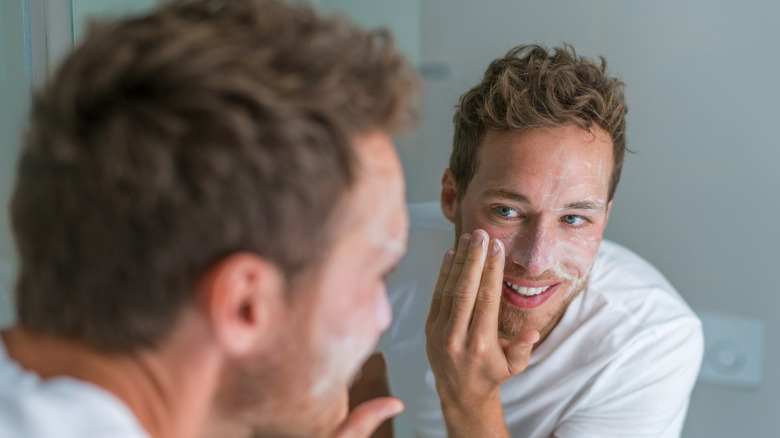 man cleaning face in mirror