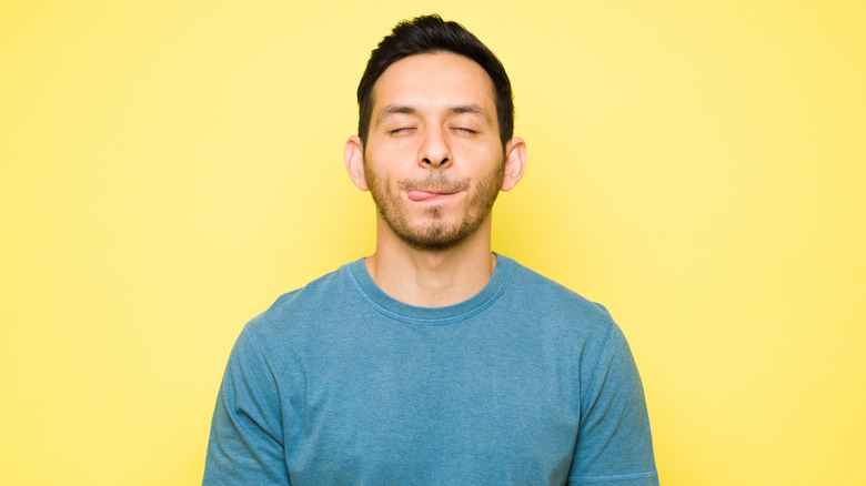 man licking lips with yellow background