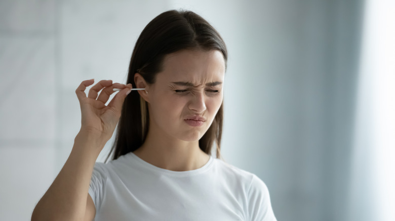 woman cleaning ears with earbud