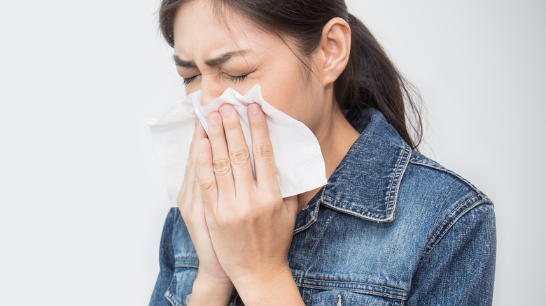 woman blowing nose into napkin