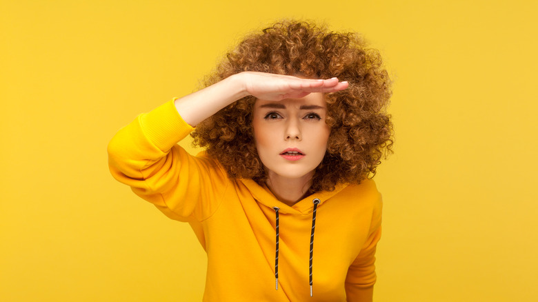 woman holds hand over her eyes as if struggling to see 