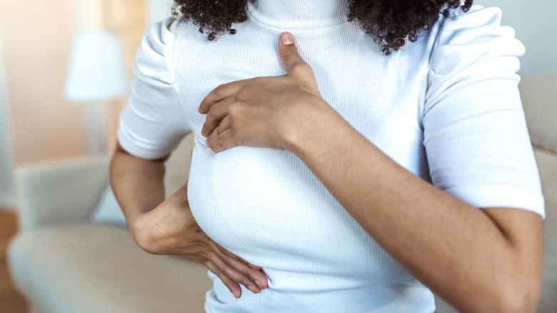 Black woman checking breast for lump