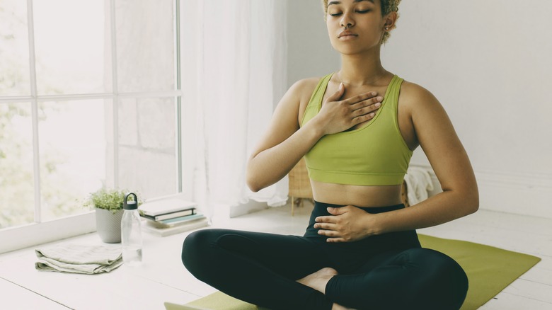 woman sitting cross-legged and breathing 