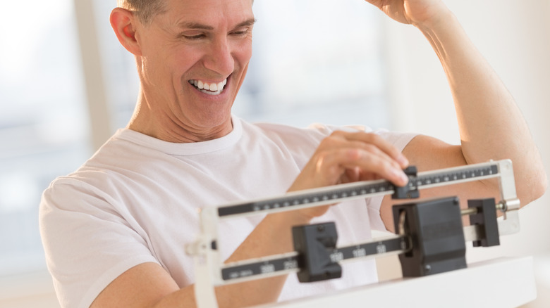 man weighing himself and celebrating the number