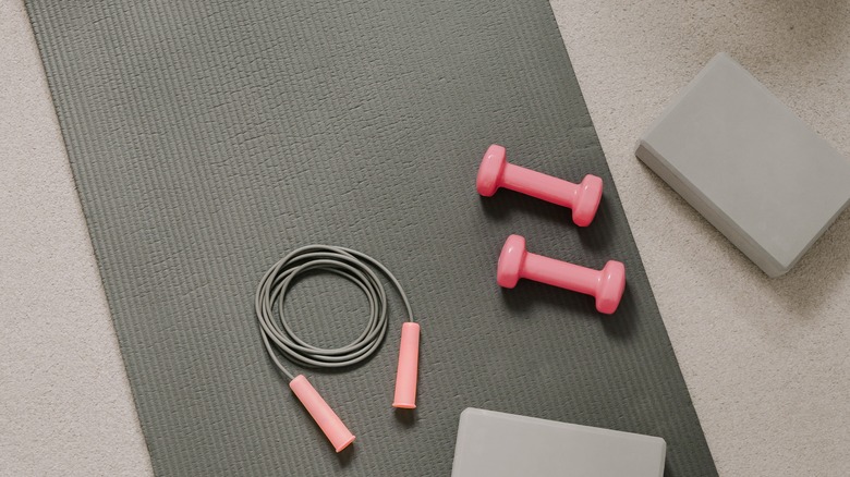 Workout mat with weights, jump rope, and yoga blocks