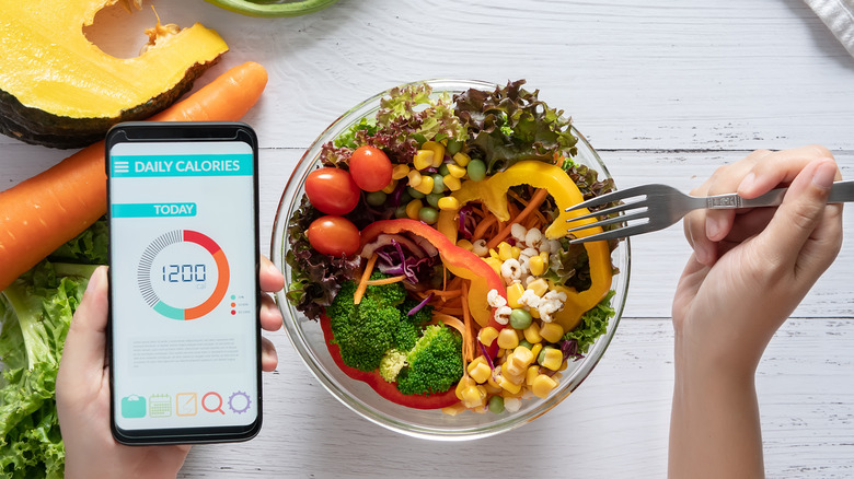 person eating a salad and using diet tracking app