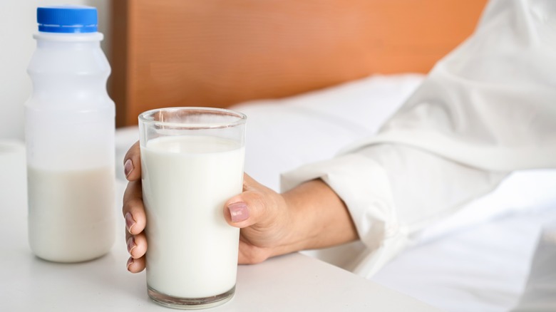 Holding glass of milk by bed
