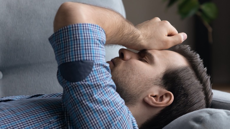 Man laying back on couch looking tired