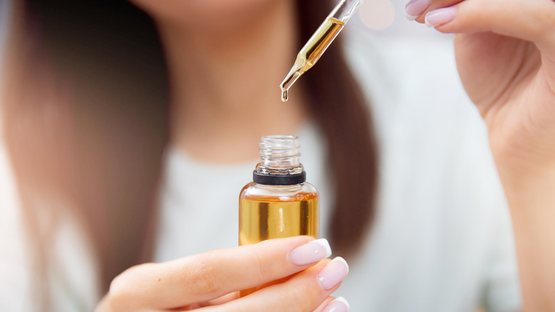 Woman holding dropper of oil