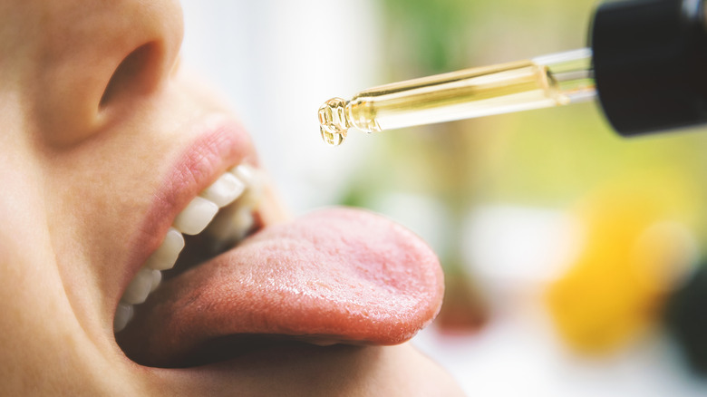 woman putting drop of cbd oil in mouth